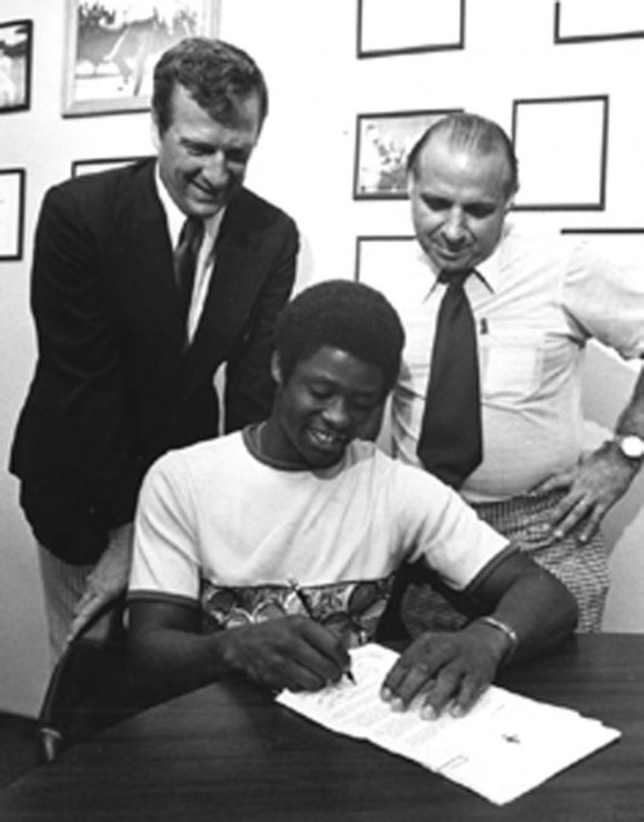 Warren Cromartie signing his first professional contract in 1973, accompanied by Mel Didier of the Expos and coach Demie Mainieri